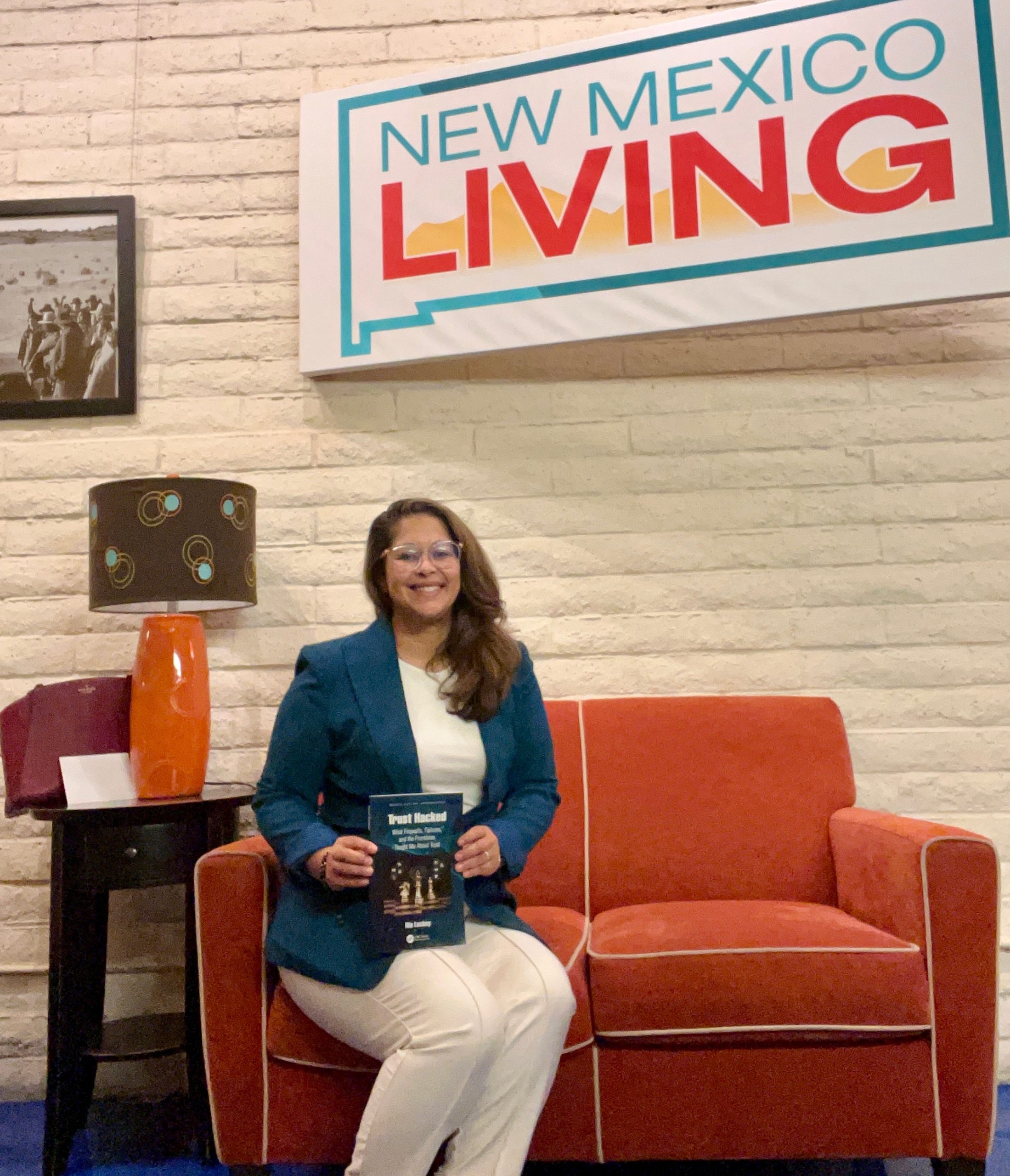 Nia Luckey on New Mexico Living holding her book Trust Hacked
